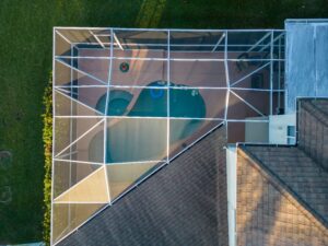 A drone shot of a modern house with a glass pool screen enclosure